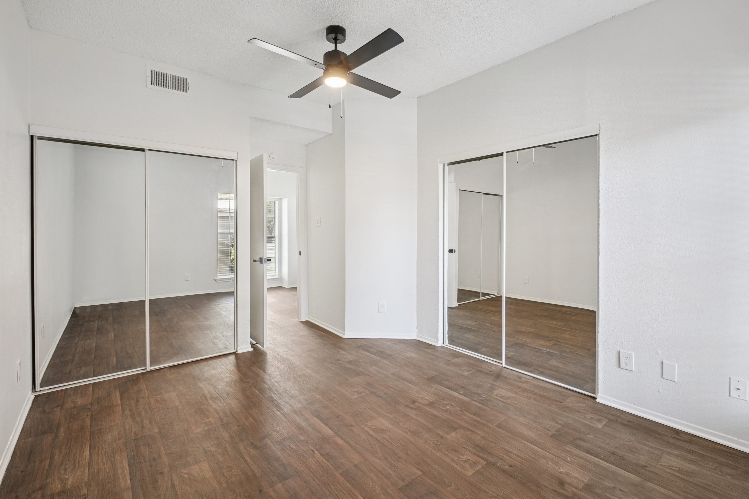 A room with a ceiling fan and sliding glass doors.